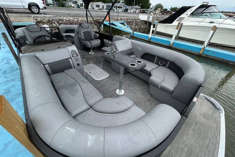 Slide: The Image of 2020 Bennington 23 SX pontoon boat with spacious gray seating and cup holders at a dock. - 3