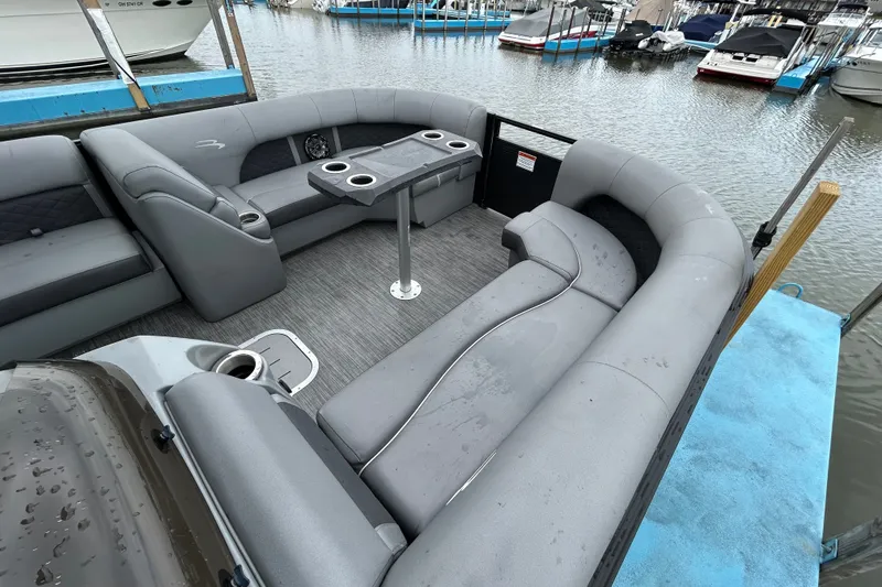 Slide: The Image of 2020 Bennington 23 SX pontoon boat with spacious seating and table, docked at marina. - 4