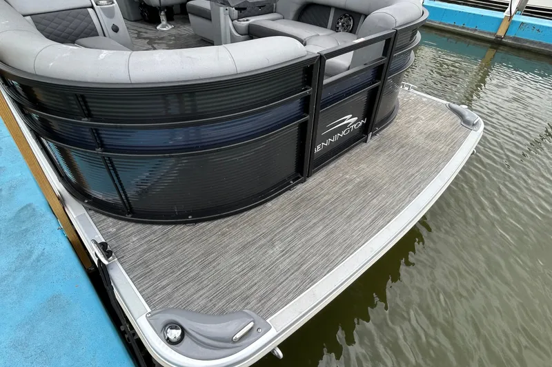 Slide: The Image of 2020 Bennington 23 SX pontoon boat docked, featuring sleek design and comfortable seating. - 2
