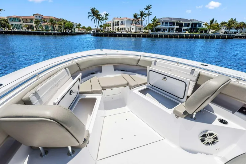 Slide: The Image of 2024 Sportsman Open 352 Center Console boat interior with seating and storage, docked by waterfront homes. - 29