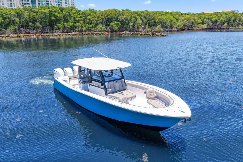 Slide: The Image of 2024 Sportsman Open 352 Center Console boat on calm water, surrounded by lush greenery. - 6