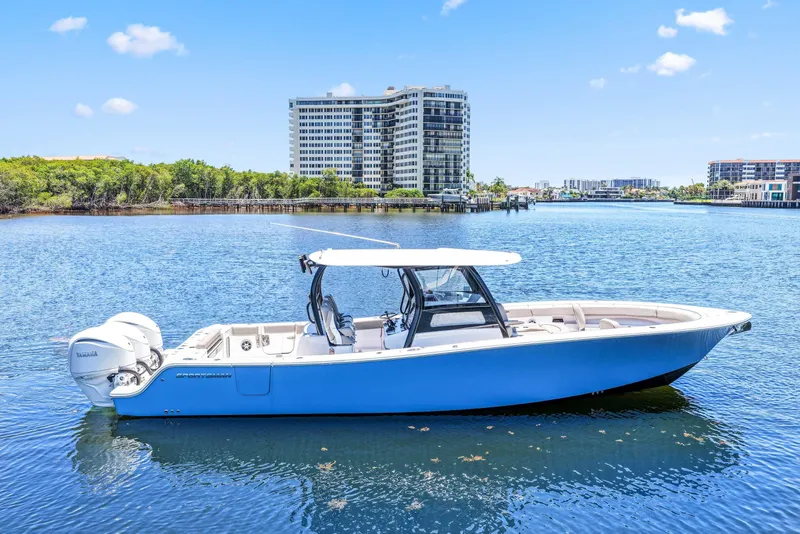 Slide: The Image of 2024 Sportsman Open 352 Center Console boat on calm water, with cityscape background. - 8
