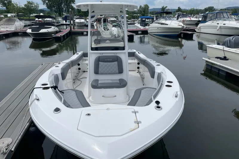 Slide: The Image of 2024 NauticStar 222L Offshore boat docked in a marina, showcasing sleek design and seating. - 3