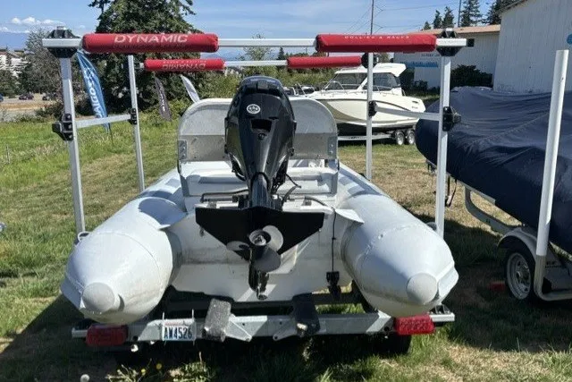 Slide: The Image of 2019 Inmar 330R-YS inflatable boat on trailer with outboard motor, parked on grass. - 1