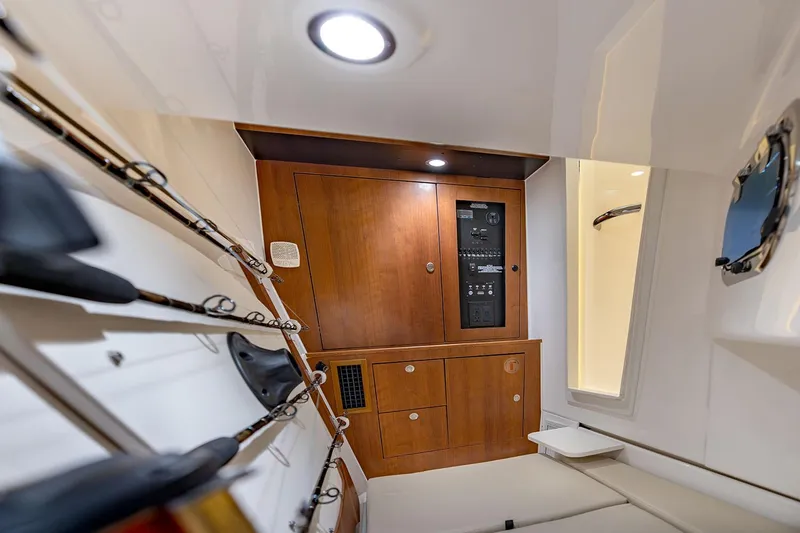 Slide: The Image of Manufacturer Provided Image: 2025 Pursuit DC 326 Dual Console cabin interior with wooden cabinetry and fishing rod storage. - 14