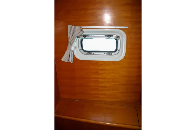 Slide: The Image of Interior view of a 2001 Lagoon 410 yacht with a small window and curtain. - 35