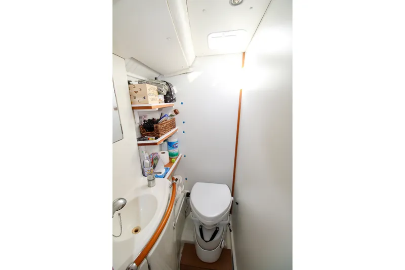 Slide: The Image of Compact bathroom in a 2001 Lagoon 410 yacht with sink, toilet, and storage shelves. - 64