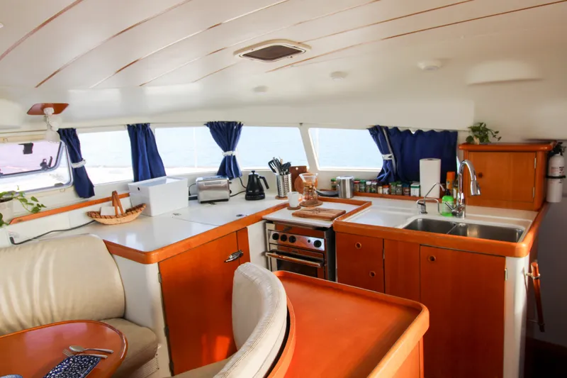 Slide: The Image of Interior of 2001 Lagoon 410 catamaran kitchen with wooden cabinetry and ocean view. - 45
