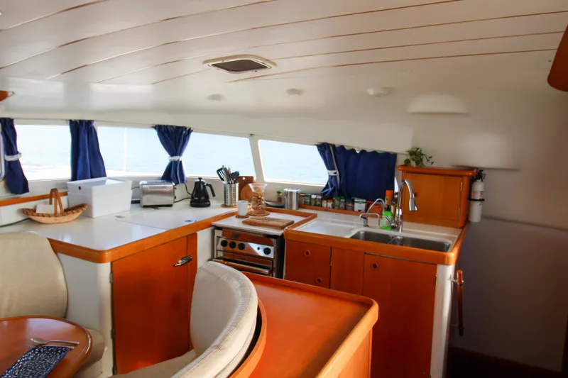 Slide: The Image of Interior of 2001 Lagoon 410 catamaran kitchen with wooden cabinetry and ocean view. - 53