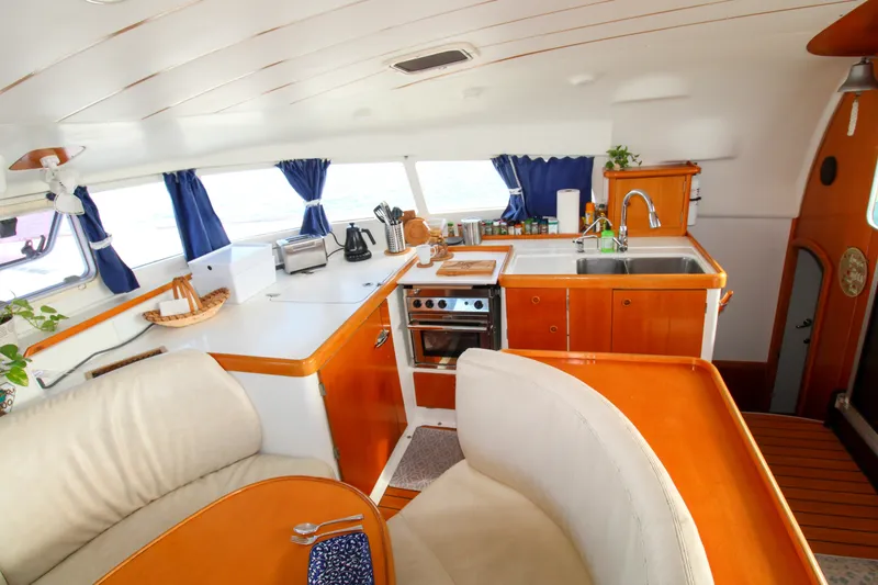 Slide: The Image of Interior of 2001 Lagoon 410 catamaran featuring a modern kitchen with wooden cabinetry. - 51