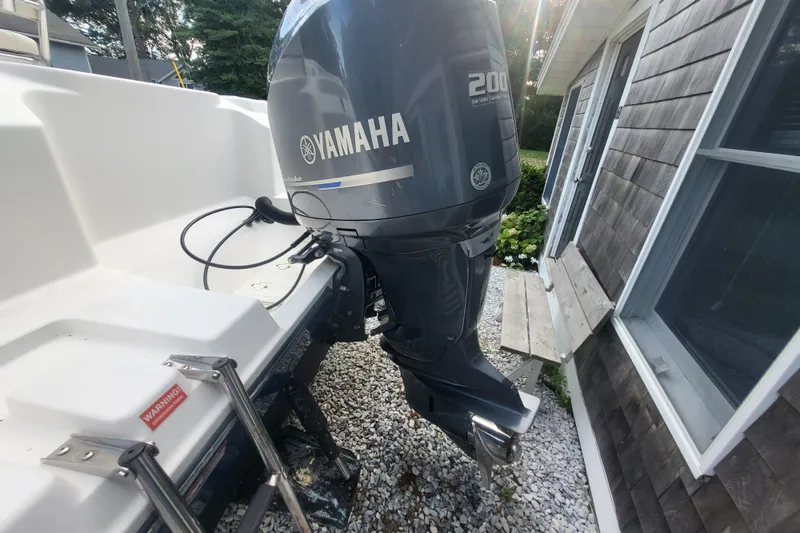 Slide: The Image of 2012 Cobia 217 Center Console with Yamaha 200 outboard motor, parked near a house. - 33