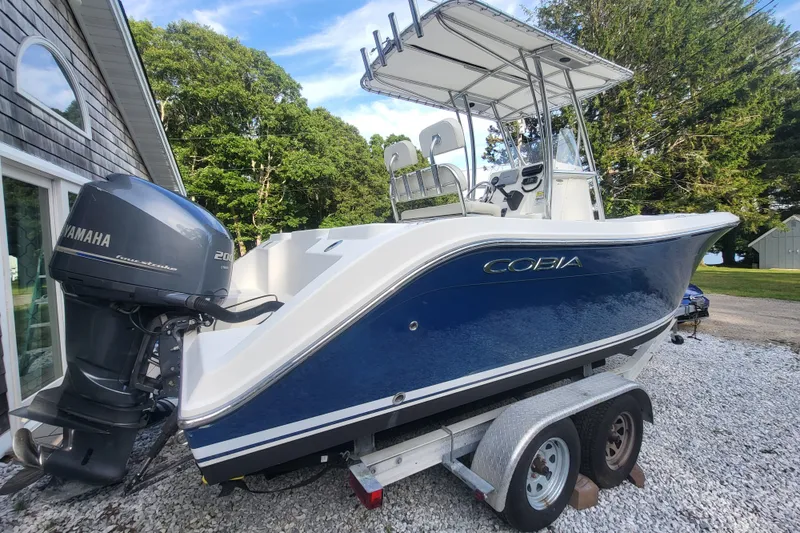 Slide: The Image of 2012 Cobia 217 Center Console boat with Yamaha engine on trailer, parked outdoors. - 2