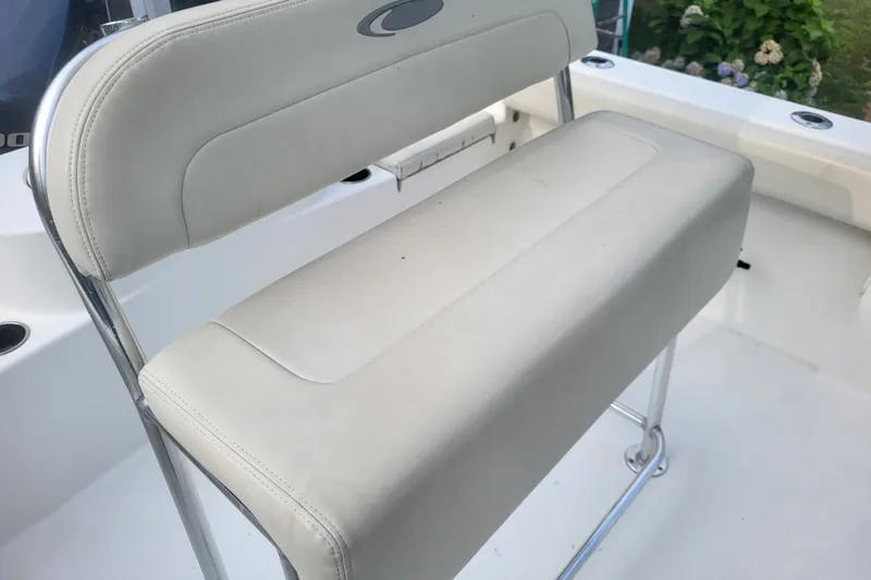 Slide: The Image of 2012 Cobia 217 Center Console boat seat with white upholstery and chrome frame. - 13