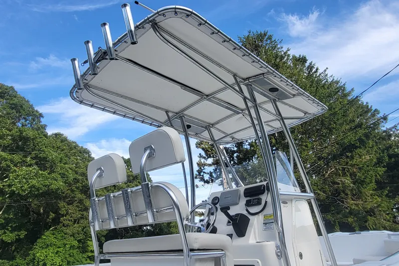 Slide: The Image of 2012 Cobia 217 Center Console boat with T-top and dual seats against a clear sky. - 7