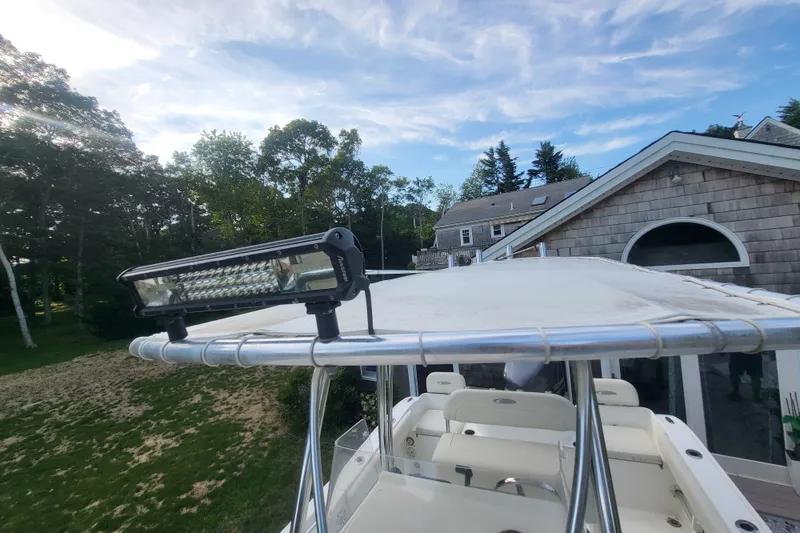Slide: The Image of 2012 Cobia 217 Center Console boat with mounted light bar, near a house and trees. - 35