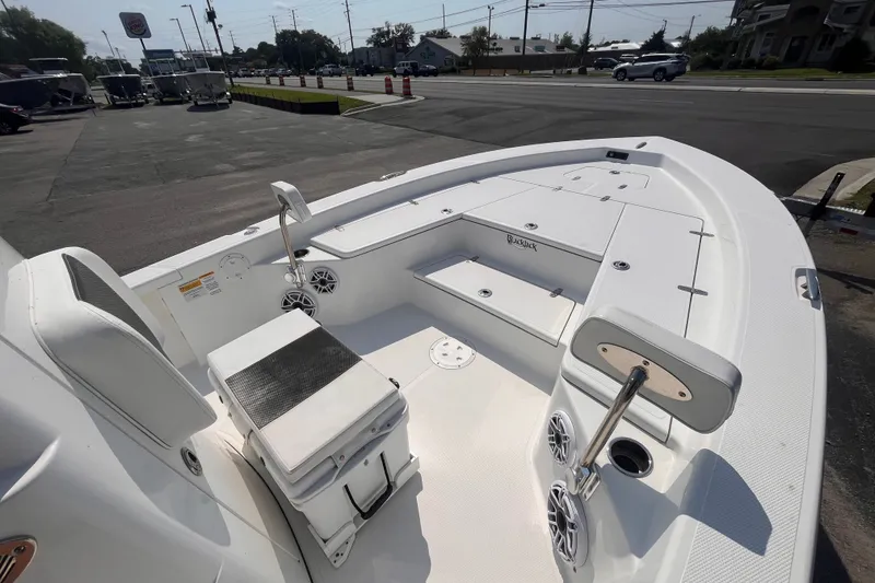 Slide: The Image of 2023 BlackJack 256 Bay boat interior with seating and storage, parked outdoors. - 10