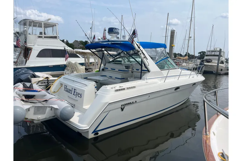 The Image of 1997 Formula 34 Performance Cruiser docked at marina, featuring blue canopy and "Hazel Eyes" name. - 0