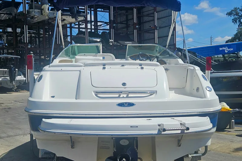 Slide: The Image of 2003 Chaparral 215 SS boat docked, rear view, with blue canopy and clear sky background. - 4