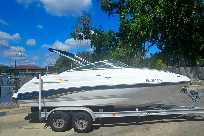 Slide: The Image of 2003 Chaparral 215 SS boat on trailer, parked near a dock under a clear blue sky. - 2
