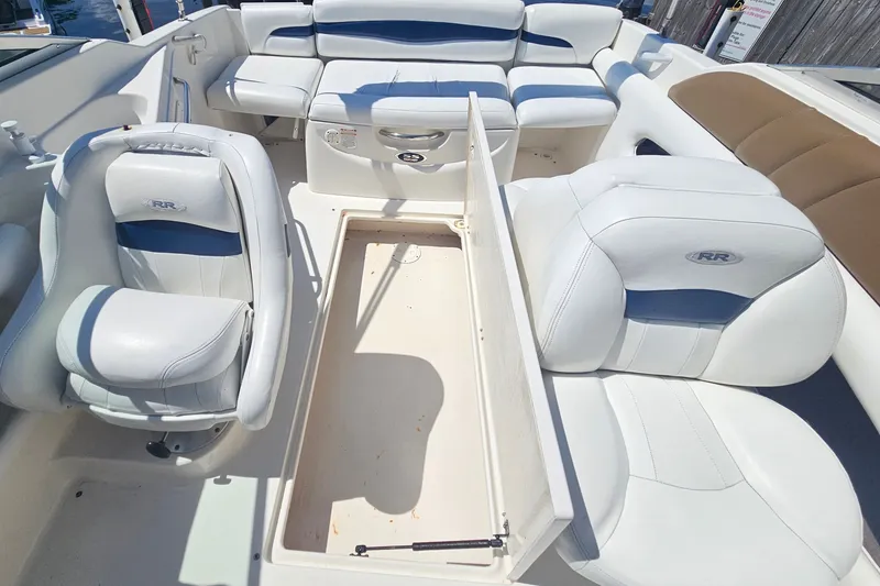Slide: The Image of 2003 Chaparral 215 SS boat interior with white and blue seating, open storage compartment. - 22