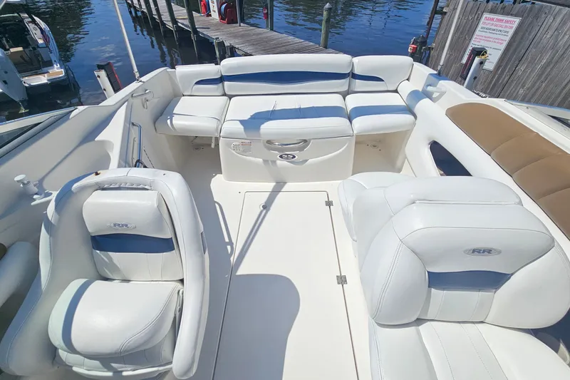 Slide: The Image of 2003 Chaparral 215 SS boat interior with white seating and blue accents at a dock. - 21