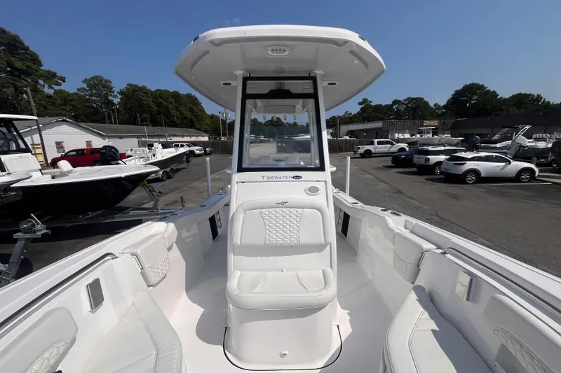 Slide: The Image of 2027 Tidewater 232 LXF boat interior with seating, parked in a marina under clear skies. - 12
