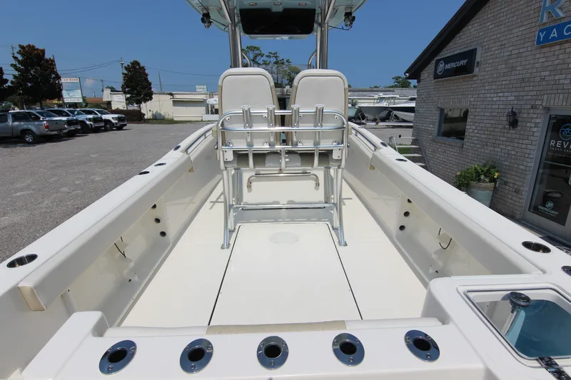 Slide: The Image of 2024 Bulls Bay 255 Center Console boat, spacious deck, rod holders, and seating, parked outdoors. - 15