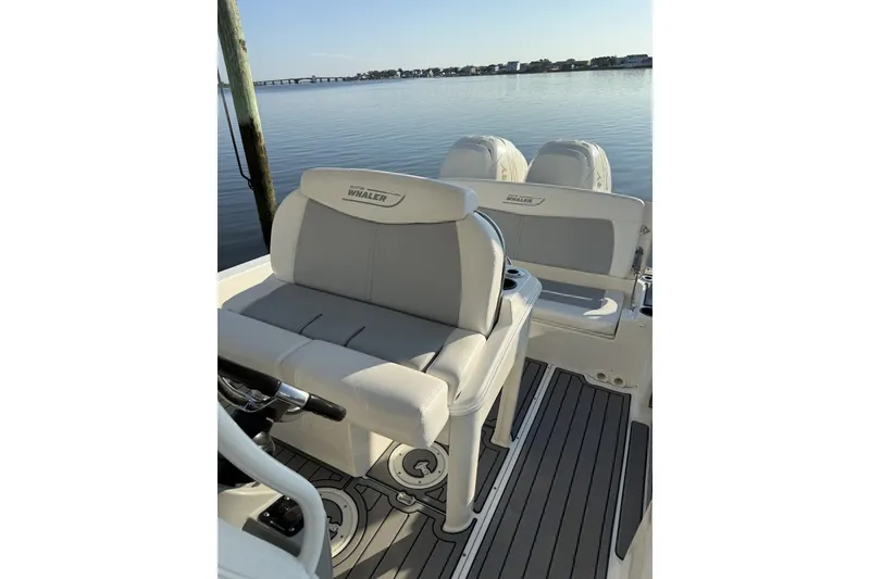 Slide: The Image of 2015 Boston Whaler 270 Dauntless boat interior with seating and dual engines on calm water. - 13