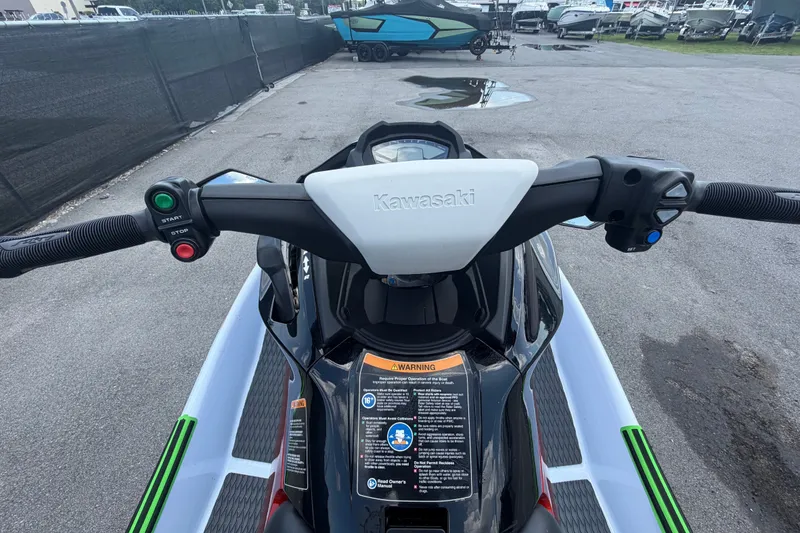 Slide: The Image of 2024 Kawasaki Jetski STX 160X handlebars and controls, parked on pavement. - 13