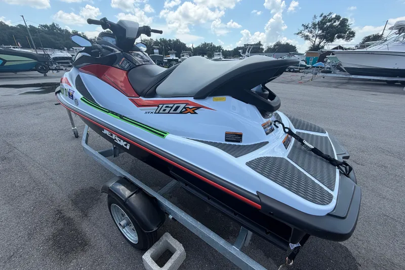 Slide: The Image of 2024 Kawasaki Jetski STX 160X on trailer, parked outdoors under a cloudy sky. - 5