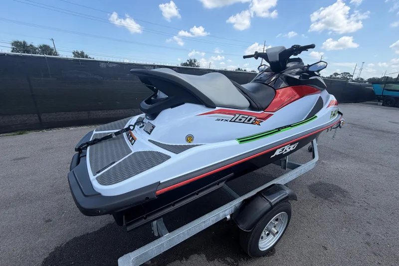 Slide: The Image of 2024 Kawasaki Jetski STX 160X on trailer, parked outdoors under a blue sky. - 2