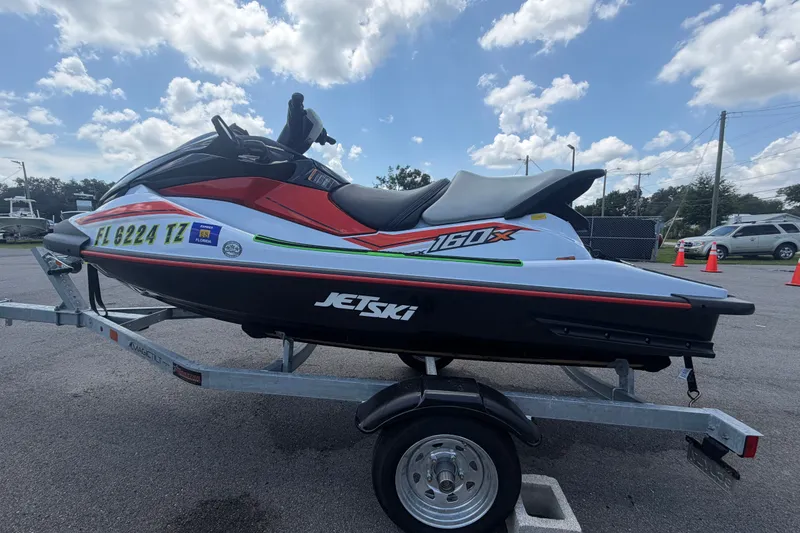Slide: The Image of 2024 Kawasaki Jetski STX 160X on trailer, parked outdoors under a cloudy sky. - 6