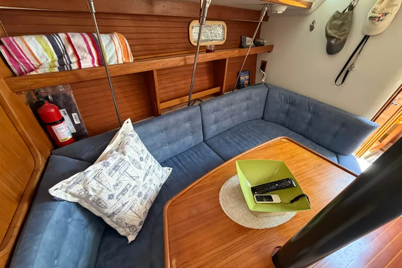 Slide: The Image of Cozy interior of a 1997 Catalina 320 sailboat with blue seating and wooden table. - 12