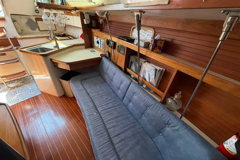 Slide: The Image of Interior of a 1997 Catalina 320 sailboat with a cozy seating area and kitchenette. - 29