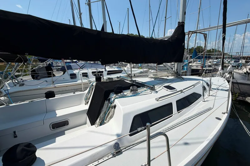 Slide: The Image of 1997 Catalina 320 sailboat docked at a marina, featuring sleek design and black sail cover. - 3