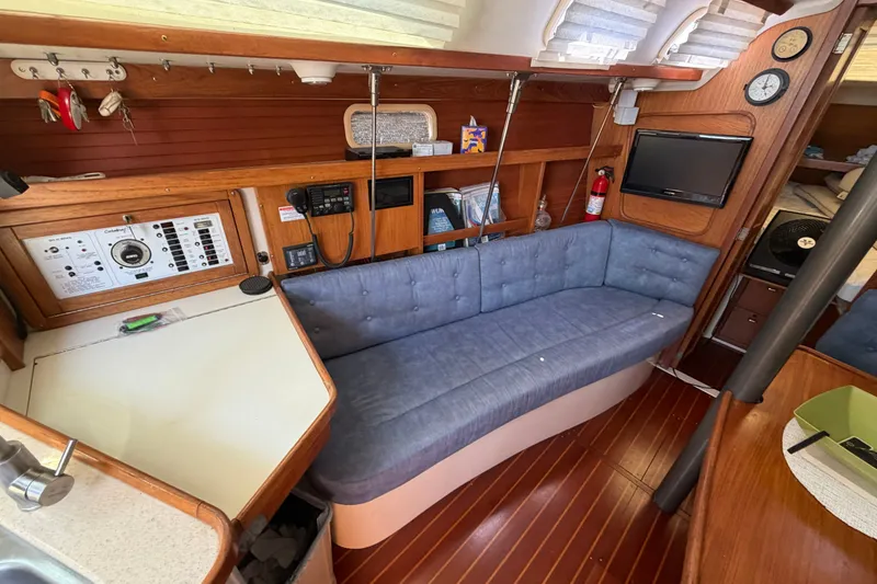 Slide: The Image of Interior of a 1997 Catalina 320 sailboat with blue cushioned seating and wooden accents. - 13