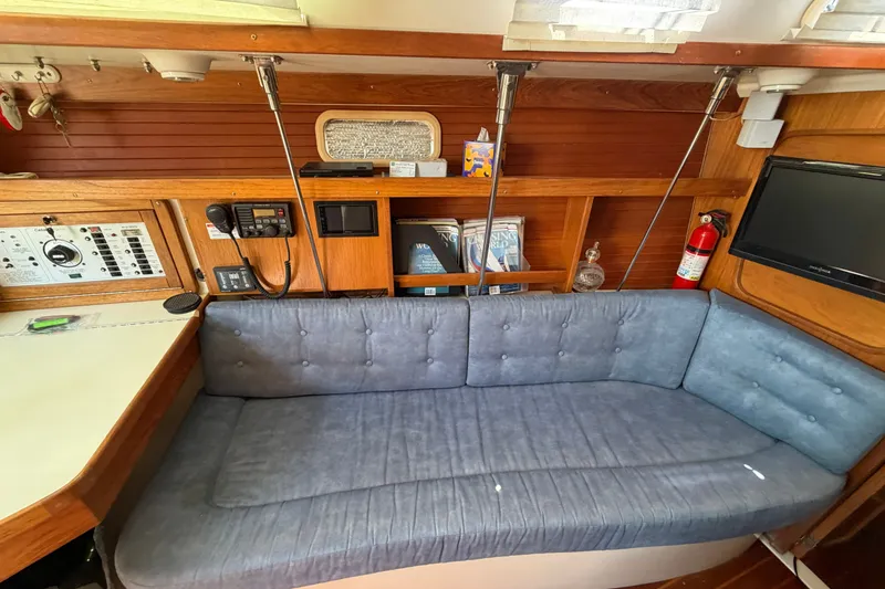 Slide: The Image of Interior of a 1997 Catalina 320 sailboat with blue cushioned seating and navigation equipment. - 15