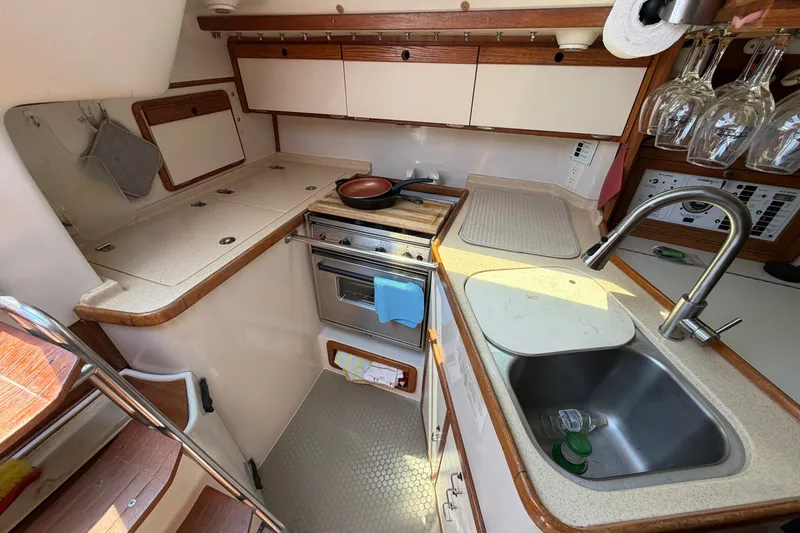 Slide: The Image of Compact kitchen in a 1997 Catalina 320 sailboat with stove, sink, and storage. - 17