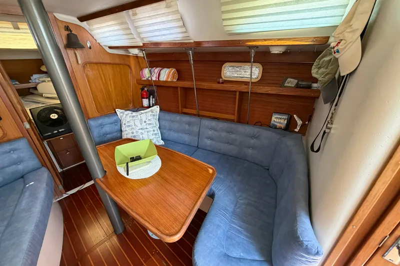 Slide: The Image of Interior of a 1997 Catalina 320 sailboat with blue seating and wooden table. - 11