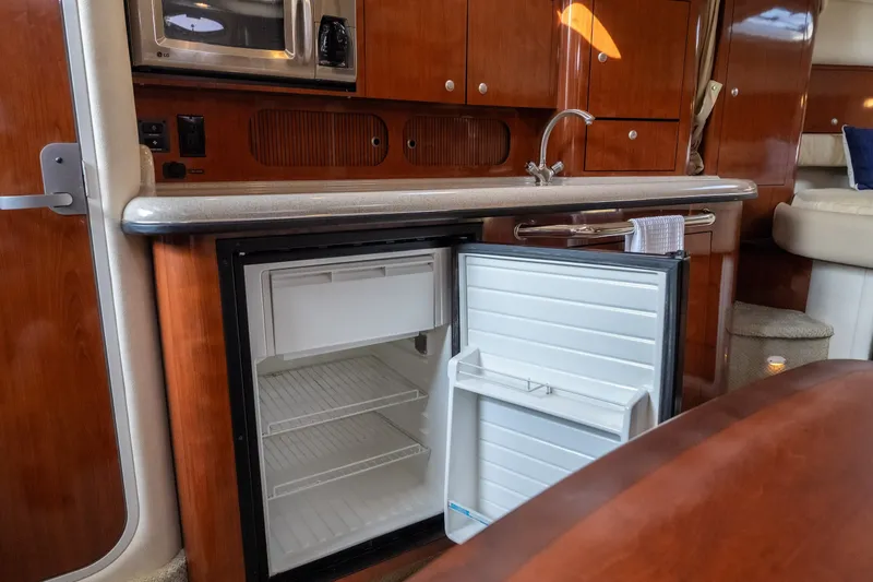 Slide: The Image of 2007 Sea Ray 340 Sundancer galley with open fridge, microwave, and wooden cabinetry. - 55