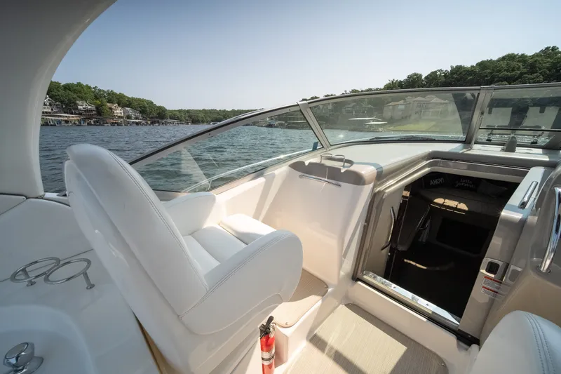 Slide: The Image of 2007 Sea Ray 340 Sundancer cockpit with white seating, overlooking serene lake and shoreline. - 17