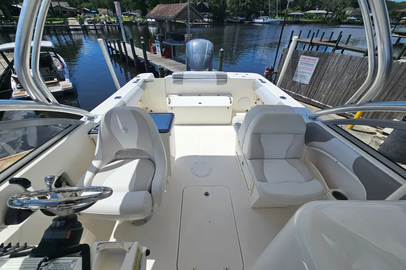 Slide: The Image of 2013 Edgewater 245CX Crossover boat interior at a dock, featuring seating and steering wheel. - 26