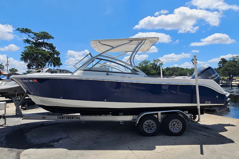 Slide: The Image of 2013 Edgewater 245CX Crossover boat on trailer under blue sky. - 6