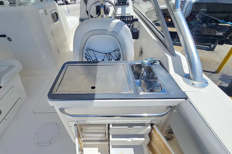 Slide: The Image of Interior of a 2013 Edgewater 245CX Crossover boat featuring a compact kitchenette. - 12