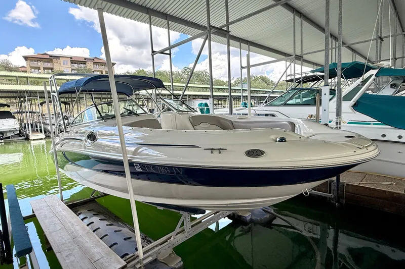 Slide: The Image of 2003 Sea Ray 240 Sundeck boat docked in a marina under a covered shelter. - 14