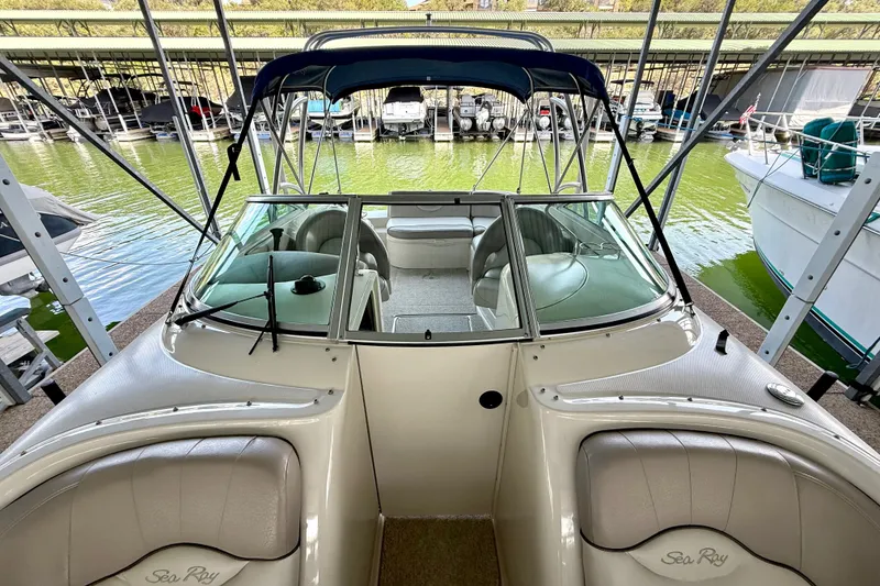 Slide: The Image of 2003 Sea Ray 240 Sundeck boat docked, featuring spacious seating and a blue canopy. - 27