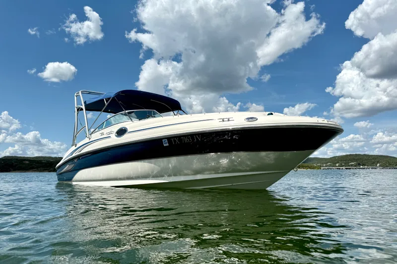 Slide: The Image of 2003 Sea Ray 240 Sundeck boat on calm water under a partly cloudy sky. - 2