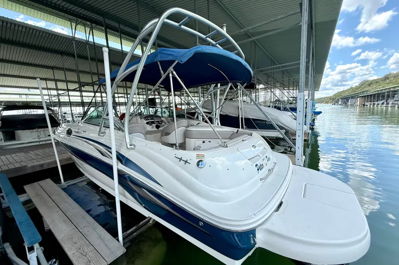 Slide: The Image of 2003 Sea Ray 240 Sundeck boat docked under a covered marina with blue canopy. - 13