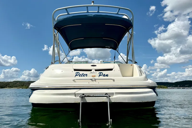 Slide: The Image of 2003 Sea Ray 240 Sundeck boat on water, blue canopy, scenic sky background. - 4