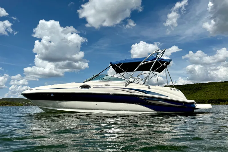 Slide: The Image of 2003 Sea Ray 240 Sundeck boat on water under blue sky with clouds. - 6